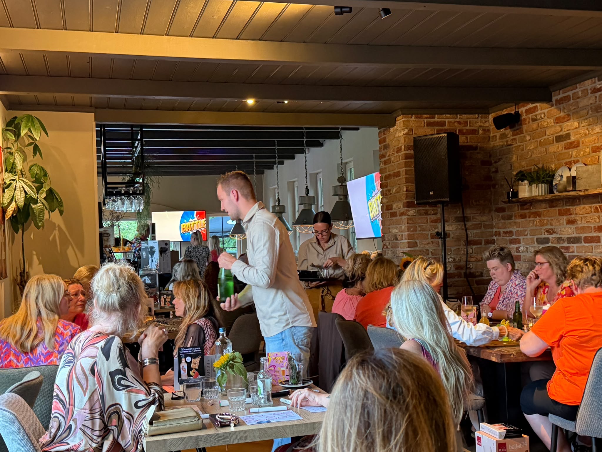Druk Battle Quiz-event in een sfeervol restaurant met scherm en publiek aan tafel